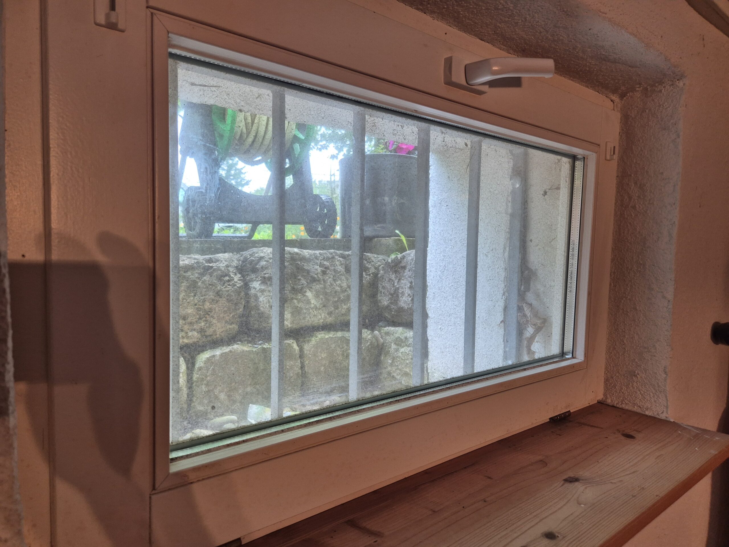 Kleines Fenster mit Sprossen, gegenüber einer Steinmauer - ideal für Gebäudereinigungszwecke.