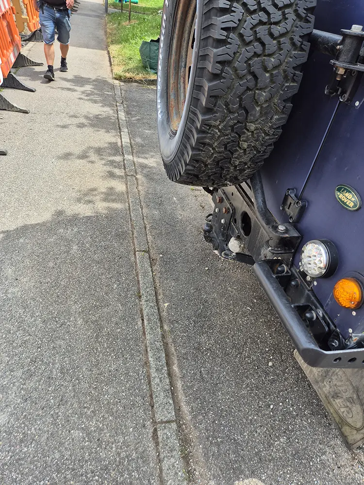 Bei der Grauflächenpflege wird das Hinterrad eines Lkw auf einen Bordstein gehoben.